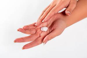 Close Up of Person using Hand Creme for Daily Hand Skin Care on White Background