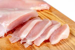 Close up of raw chicken fillet chunks on wooden kitchen board