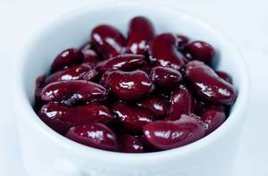 Close-up of shiny red kidney beans in white cup