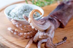 Close-up of squid head with tentacles on wooden kitchen Board