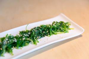 Close-up of the vegan Japanese appetizer "Goma Wakame" with seaweeds and sesame on a wooden table