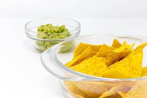 Close Up on Nacho Chips with Guacamole Avocado Dip in the background