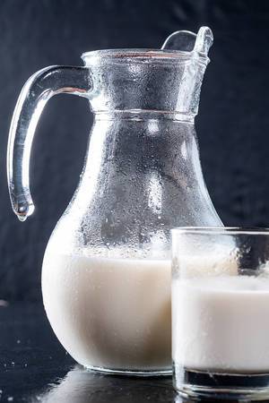 Close Up Photo of a Glass Jug and a Glass filled with cold Milk with dark Background