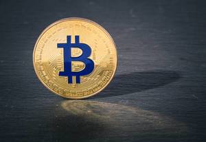 Close up photo of a golden Bitcoin on a black background