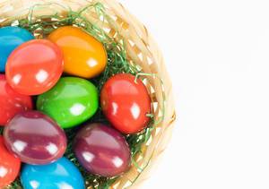 Close Up Photo of Colorful Easter Eggs in a Basket on White Background