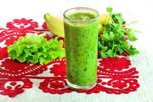 Close Up Photo of Green Healthy Smoothie with Lettuce, Herbs and Banana on a Table