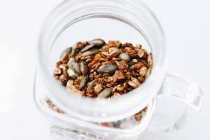 Close Up Photo of Homemade Granola with Nuts in a Glass on White Background