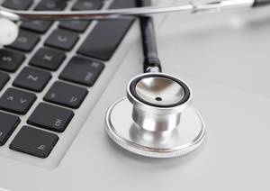 Close Up Photo of Medical Stethoscope laying on Keyboard of Laptop