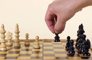 Close Up Photo of Person moving a Chess Character on Wooden Chess Board