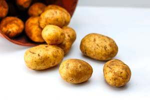 Close Up Photo of Potatoes falling out of a Bowl on white Background