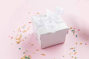 Close Up Photo of Small Ring Gift Box with Colorful Sprinkles around it on White Background