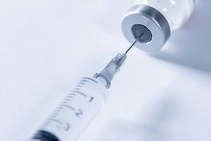 Close Up Photo of Syringe getting Liquid Medication out of a small container on White Background