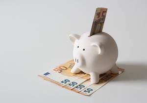 Close Up Photo of White Piggy Bank with several 50 Euro Banknotes on White Background