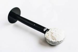 Close Up Shot of Protein Powder in a Black Spoon on white Background