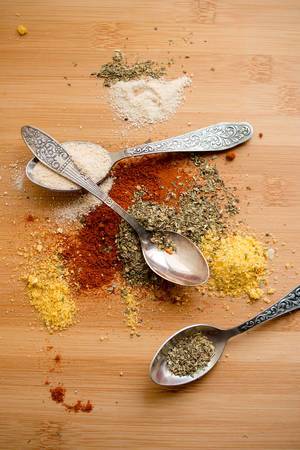Close Up Top View Photo of Different Spices with three Spoons on Wooden Table