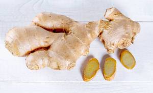 Close Up Top View Photo of Ginger with Sliced Pieces on White Wooden Table