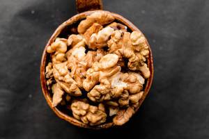Close Up Top View Photo of Walnuts in a Ceramic Cup on Dark Background