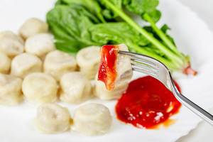 Close up vegetarian dumplings with spinach and tomato sauce on a fork (Flip 2019)
