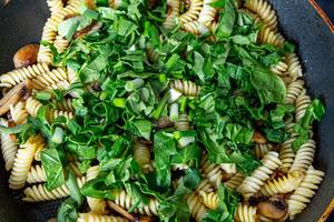 Closeup of pasta with spinach and mushrooms in a frying pan (Flip 2019)