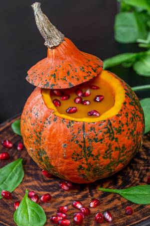 Closeup of yummy pumpkin Halloween with pomegranate in fresh spinach leaves (Flip 2019)