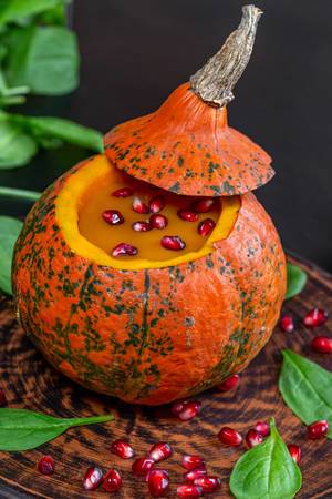 Closeup von leckerem Kürbis zu Halloween mit Granatapfel und frischen Spinatblättern