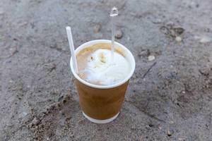 Cold Frappe Coffee with an ice cream scoop, on the beach, in a to go cup