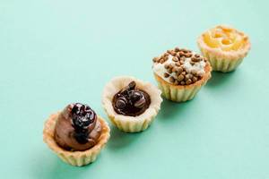 Collection of mini tarts with different flavors on blue background