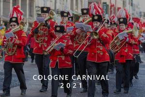 Cologne "Husaren-Korps von 1972" makes music at the Parade in red-golden uniforms with guard-hats, next to the picture title "Cologne Carnival 2021"