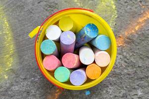 Colored chalk in a yellow bucket. Top view (Flip 2019)