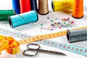 Colored sewing thread and bobbin with measuring tape, scissors and needles