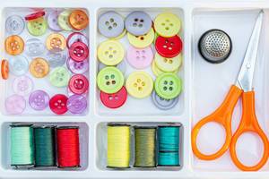 Colorful buttons, thread with scissors and thimble in a sewing box