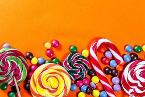 Colorful lollipops and candies on orange background