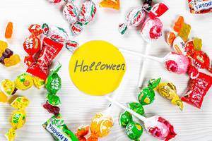 Colorful lollipops and candies on white background with Halloween tag. Top view