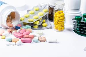 Colorful pills and capsules in blisters and scattered on a white background