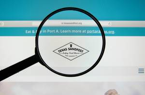 Computerbildschirm mit geöffneter Internetseite des Texas Sandfest mit Lupe über Logo