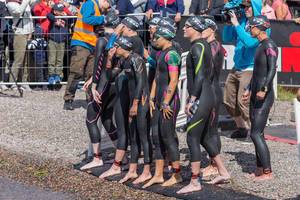 Concentrated professional athlete Laura Matthews with other pro athletes and women at the start of an Ironman 70.3, shortly before the swim discipline
