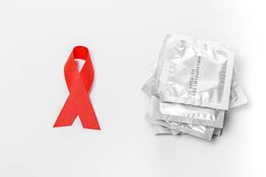 Condoms and red ribbon on a white background. The concept of protection against sexually transmitted diseases (Flip 2019)