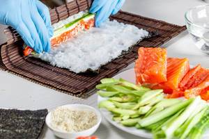 Cook preparing sushi with salmon and avocado