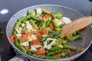 Cooking green asparagus with penne pasta, tomato and mozzarella