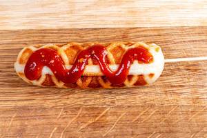 Corn dog with ketchup on wooden background