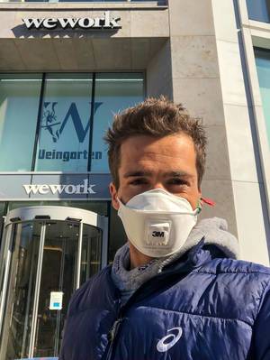 Coronavirus and WeWork. Man with FFP3 mask in front of office