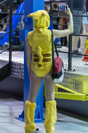 Cosplay at Gamescom: Woman in Pikachu Costume with Pokeball bag takes a selfie