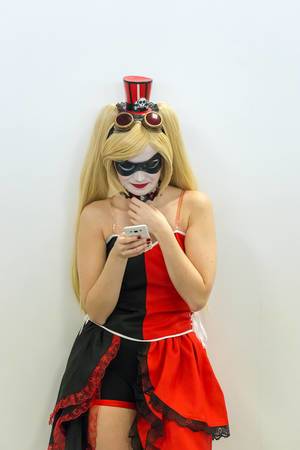 Cosplayerin mit rot-schwarzem Kleid und Schminke schaut auf ihr Handy