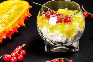 Cottage cheese with fresh kiwano and red currant berries on a black background (Flip 2020)