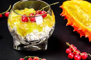 Cottage cheese with fresh kiwano and red currant berries on a black background