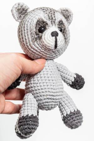 Crochet toy raccoon in hand closeup