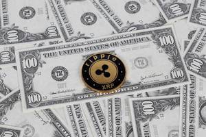 Cryptocurrency ripple (XRP) coin is on spread US dollar banknotes