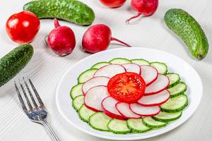 Cucumber, radish and tomato sliced on a plate on a white table with ingredients (Flip 2019)