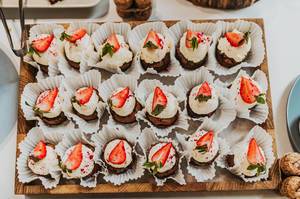 Cupcakes mit Sahne und Erdbeere auf einer Holzplatte