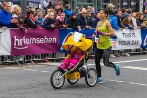 Dame nimmt mit ihrem Kind beim Frankfurter Marathon teil im Kinderwagen